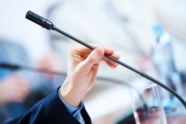 Microphone held in hand of person presenting to attorney audience